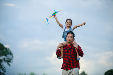 Asian child girl and father with a kite running and happy on meadow in summer in nature