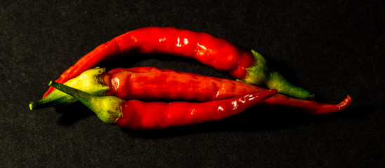 Three red hot habanaro chilies on black background