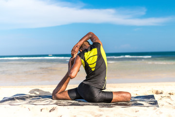 Asian yoga man practice yoga on the beach with a clear blue sky background. Yogi on the tropical beach of Bali island, Indonesia.