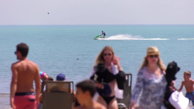 seadoo jetski races along water with beach crowd foreground 4k