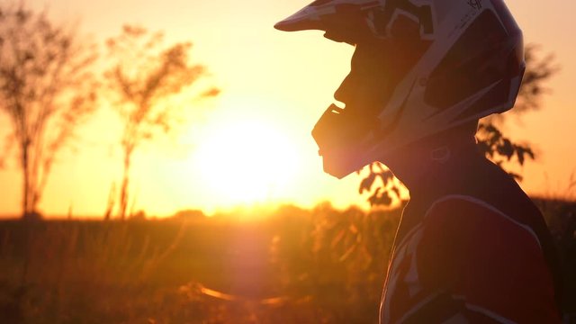 motocross rider puts his helmet on in sunset 4k 24fps close up