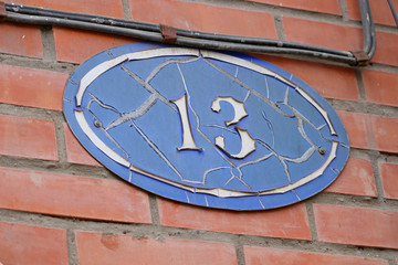 number 13 thirteen on the wall of an old house, a baker's dozen