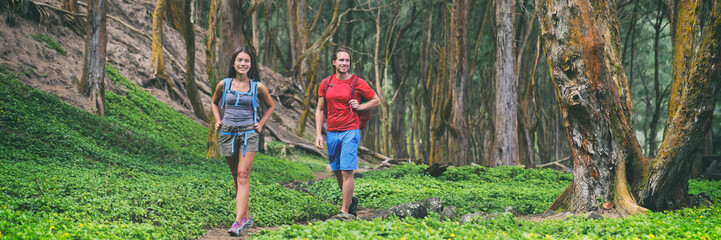 Hiking couple tourists walking in forest panoramic lansdcape banner. Travel background vacation nature rainforest landscape, happy hikers people with backpacks.