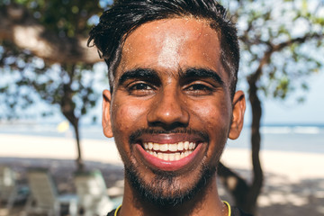 Close up portrait of young smiling asian indian yoga man outside. Park, beachside. Bali island.