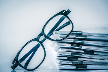 Close up the black reading eyeglasses on stacking of office paper , business working document and...
