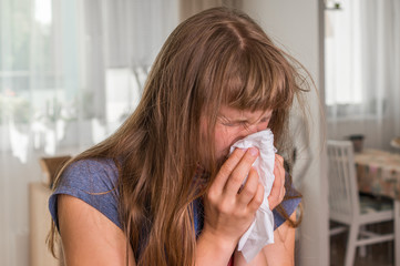 Sick woman with flu or cold sneezing into handkerchief