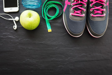 Fitness healthy concept,sneakers,apple,water and smart phone on black background ,top view