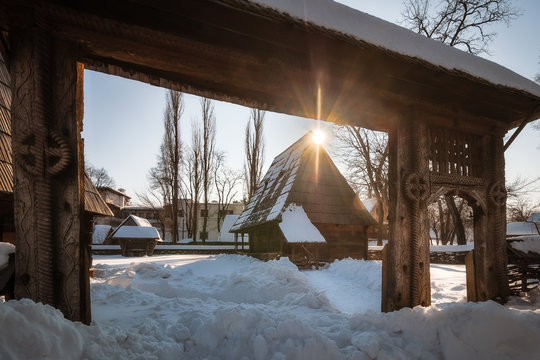 Sun star warming up a traditional Romanian homestead covered in heavy snow