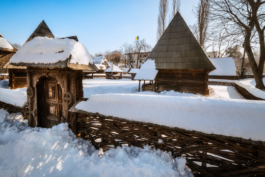 Traditional handcrafted gate and a rural Romanian homestead covered in snow