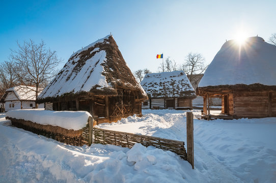 Sun warming up a traditional Romanian homestead covered in heavy snow