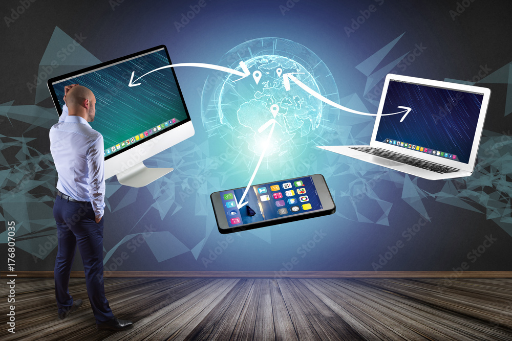 Poster businessman in front of a wall with computer and devices displayed on a futuristic interface with in