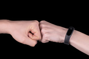 The image close-up of the collision of two fists on a black background. The concept of confrontation, competition or friendship