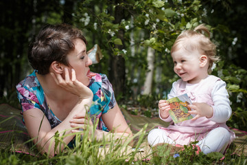 Mother and daughter have fun in the park and apple tree with white flowers