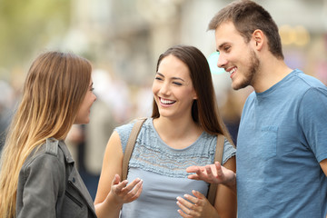 Three smiling friends talking standing on the street