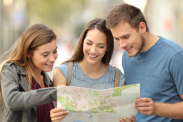 Three tourists consulting a paper map on the street