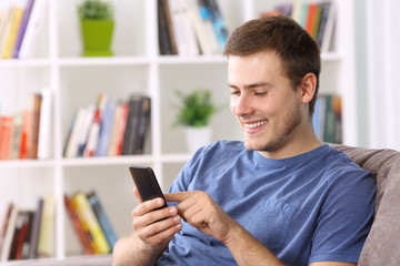Guy using a smart phone on a sofa at home