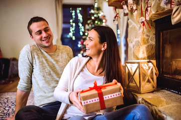 Couple in front of fireplace. Christmas time.