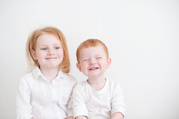 Funny brother and sister are sitting side by side