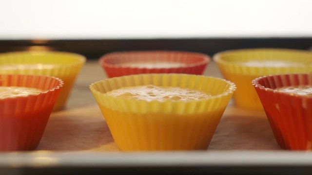 Baking sheet with muffins in hot oven timelapse. View from inside of the oven. Making homemade muffins cupcakes baked in oven. Quick sweet dessert for breakfast. Using colorful silicone baking molds.