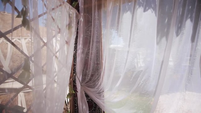 Color footage of a baldaquin with wind blowing in the curtains.