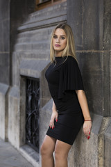 Young blonde woman wearing black dress on street