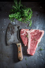 Raw t-bone steak with salt and rosemary