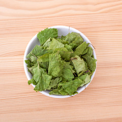 birch leaves  / Top view of a porcelain bowl with dried birch leaves on a wooden background