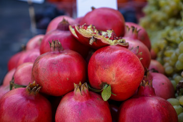 Piles of fresh beautiful shiny dark red pomegranate fruit selling in local city market with blurred background