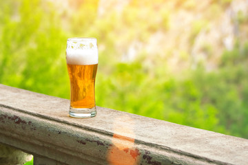 Glass of beer on the edge of the handrail in the sunlight