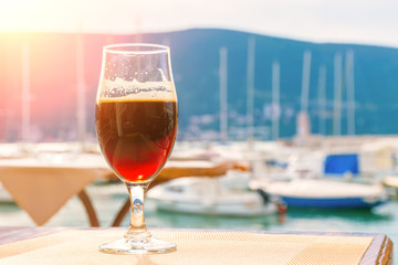 Glass of dark beer on the background of the berth for yachts