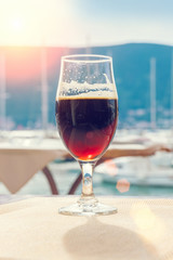 Glass of dark beer on the background of the marina