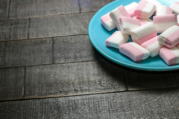 Pink marshmallows on a dark background in a blue plate