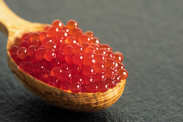 red caviar in a spoon on a black slate background