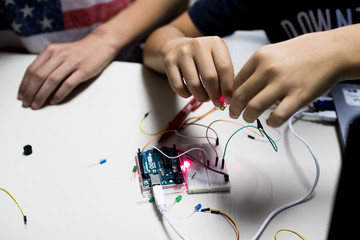 two children build a prototype circuit with a red laser controlled by a microcontroller. STEAM and...