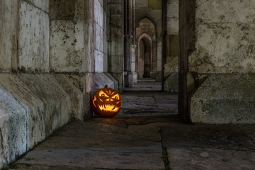 Halloween Kürbis vor einer antiken Holztür und Steinmauer einer Kirche, Deutschland