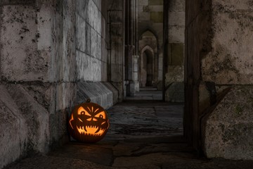 Halloween Kürbis vor einer antiken Holztür und Steinmauer einer Kirche, Deutschland