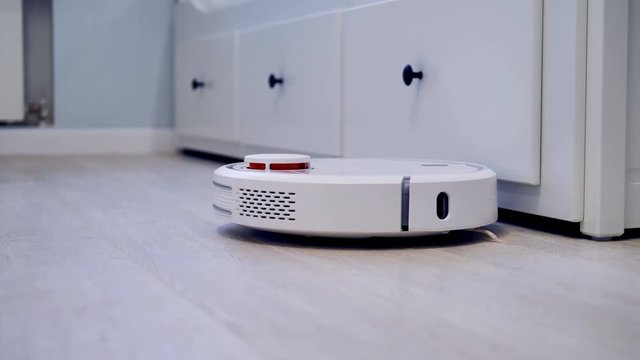 A robotic vacuum lightly connects with rooms furniture.  