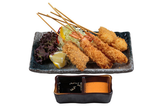 Isolated Mix tempura stick (Shrimp, salmon and quail eggs) served with slice cabbage, red oak lettuce and sliced lemon with ponzu and thousand island sauce in stone plate.