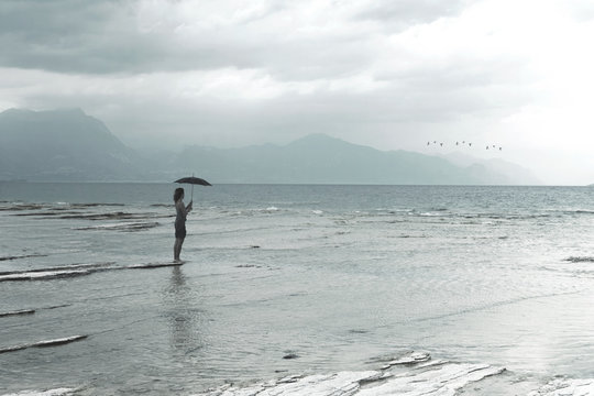 lonely woman looks at infinity and uncontaminated nature on a stormy day