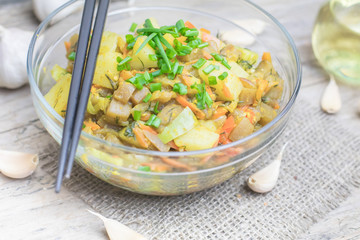 Homemade nutritional vegetable ragout in glass plate bowl on rustic old wooden table. Vegan or vegetarian food diet. Selective focus.