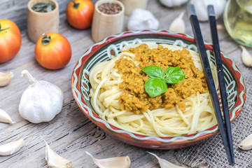 Soy vegan protein marinara spaghetti pasta in ceramic bowl with chopsticks on wooden background. Protein albumen source. Vegan vegetarian nutritional food.