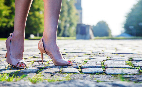 legs of a woman standing on a paving stone