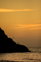 silhouettes on a rock by the sea at sunset