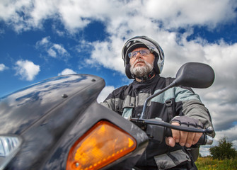 elderly motorcyclist wearing a jacket and glasses with a helmet