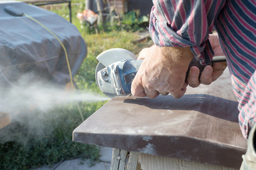 Construction worker cutting concrete plate for fence fundation using a cut-off saw.