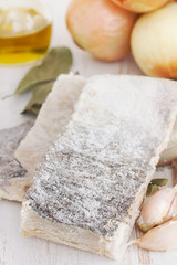 salted dry codfish with oil, garlic and onion on wooden background