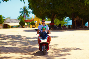 father with son riding on scooter through the Thailand