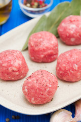 raw meatballs on the dish on wooden background