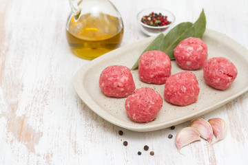 raw meatballs on the dish on wooden background