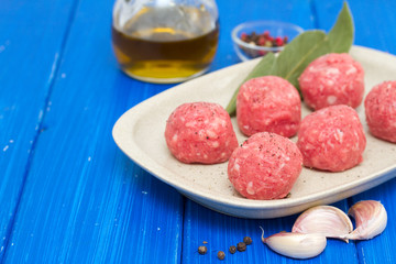 raw meatballs on the dish on wooden background